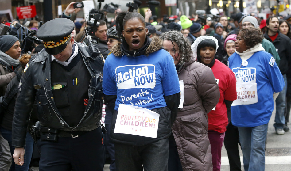 A Chicago police officer takes several protesters into custody on Wednesday, during an act of civil disobedience during a march and demonstration of opponents to a plan to close 54 Chicago Public Schools. Charles Rex Arbogast/AP A Chicago police officer takes several protesters into custody on Wednesday, during an act of civil disobedience during a march and demonstration of opponents to a plan to close 54 Chicago Public Schools. Charles Rex Arbogast/AP