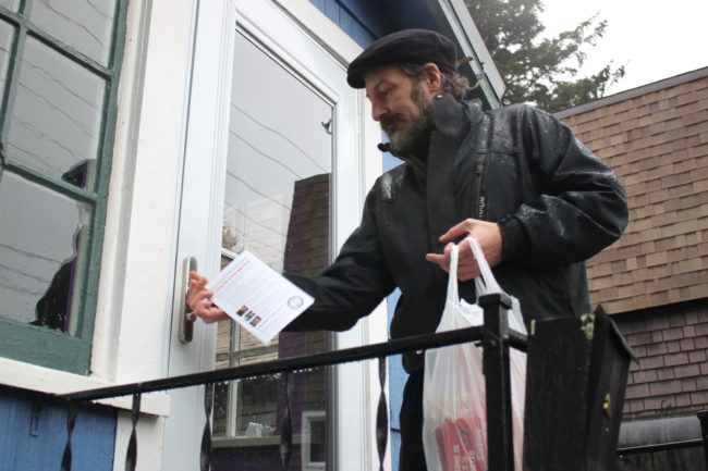 Yes on 2 volunteer Ben Wilcox leaves a door hanger on a house a few days before election. (Photo by Lisa Phu/KTOO)