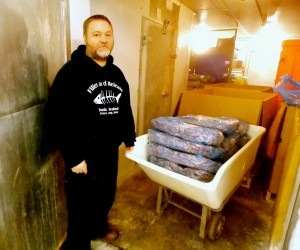 Seth Scrimsher stands in one of Tonka’s freezers with blocks of frozen pink shrimp. (Photo by Angela Denning/KFSK)