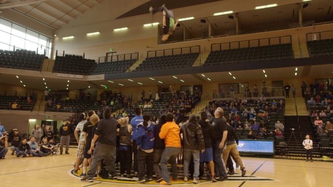 Nick Hanson using his third jump on blanket-toss to exhibit control and focus during a backflip, and sticking the landing. (Photo by Hanna Craig/Alaska Public Media)