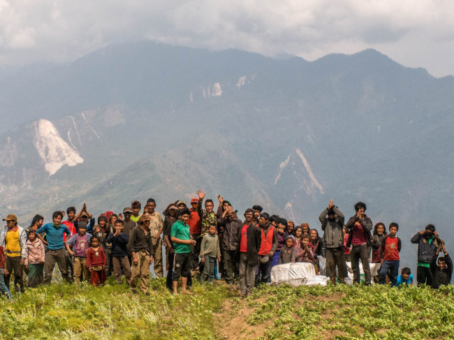 Nepalese villagers wave after collecting aid dropped by an Indian helicopter in Khanigaun, Nepal. David Ramos/Getty Images