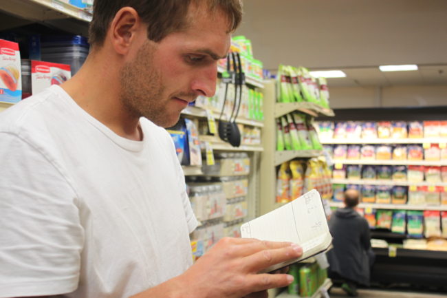 Vincent Colliard shops for groceries prepared with a list of how many kilograms he needs of each item. (Photo by Lisa Phu/KTOO)
