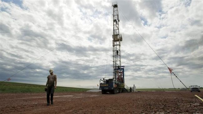 An oil worker walks away from a derrick near Williston, North Dakota. Lower oil prices are causing financial worries in some states that rely heavily on oil taxes. (AP)