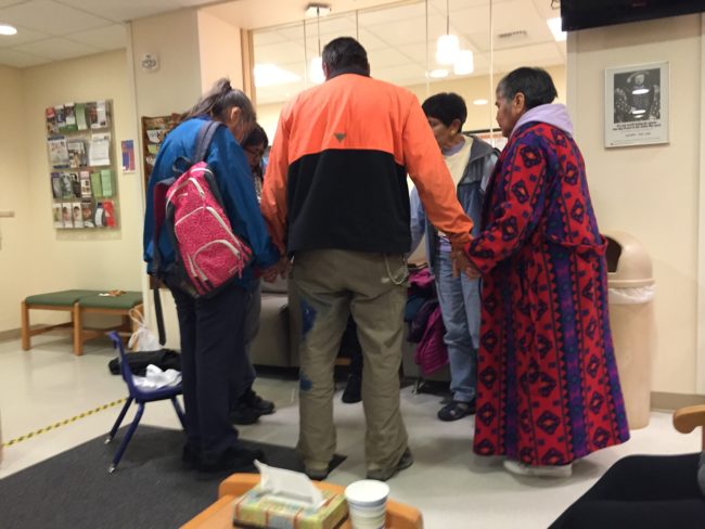 Family and friends of plane crash survivor Ernestine Hanlon-Abel of Hoonah pray together at Bartlett Regional Hospital Friday night. (Photo by Lisa Phu/KTOO)