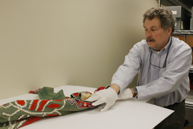 Chuck Smythe unrolls the tunic from storage. (Photo by Elizabeth Jenkins/KTOO) 