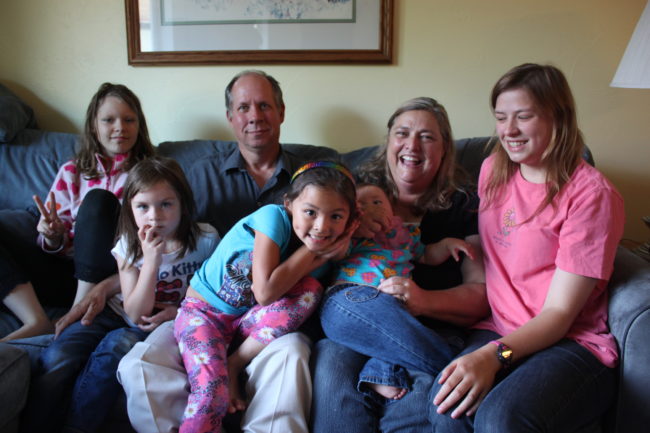 The Lohrey family. From left to right: Elena, Kylie, John, Kristyanna, Diane (holding a foster child) and Emilyanne. Elena, Kylie and Kristyanna have all been diagnosed with FASD. (Photo by Lisa Phu/KTOO)