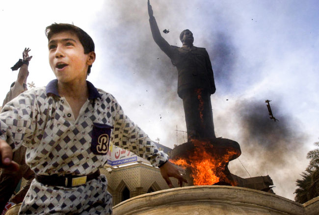 An Iraqi boy cheers as a statue of ousted Iraqi President Saddam Hussein is set ablaze during an impromptu celebration on the streets of Baghdad on April 12, 2003. Scott Nelson/Getty Images