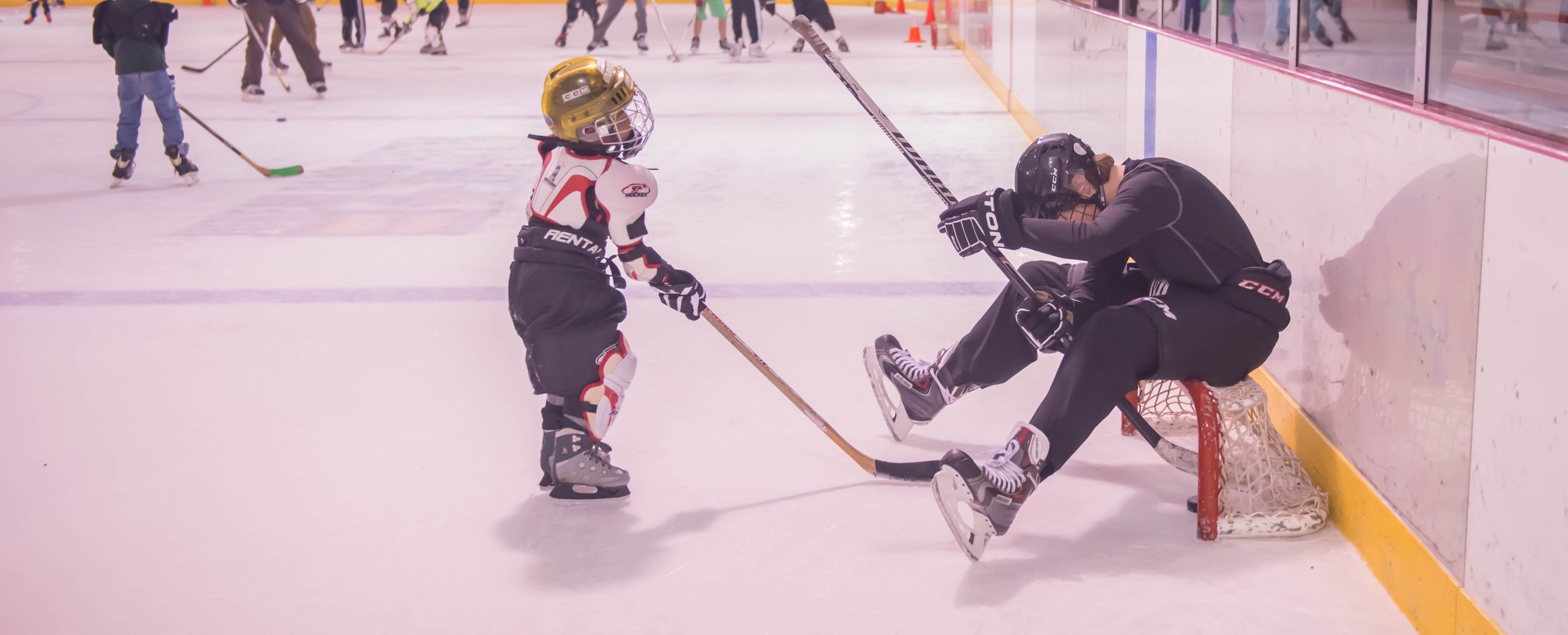 Owen Squires (right) looks for the puck shot by Joshua Mazon during JDIA’s Learn to Play afternoon at Treadwell Ice Arena. (Photo by Steve Quinn)