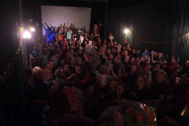 Audience members hold up their gifts during the 2014 Christmas Bazaar Extravaganza at the Gold Town. (Photo Courtesy of Colette Costa)