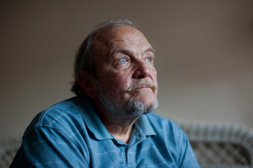 Tom Wall sits in his bedroom before the Make Room concert begins on Jan. 18. Around 20 people gathered in Wall's small apartment to attend the concert and to help him, and others like him, pay the rent. Brandon Chew/NPR