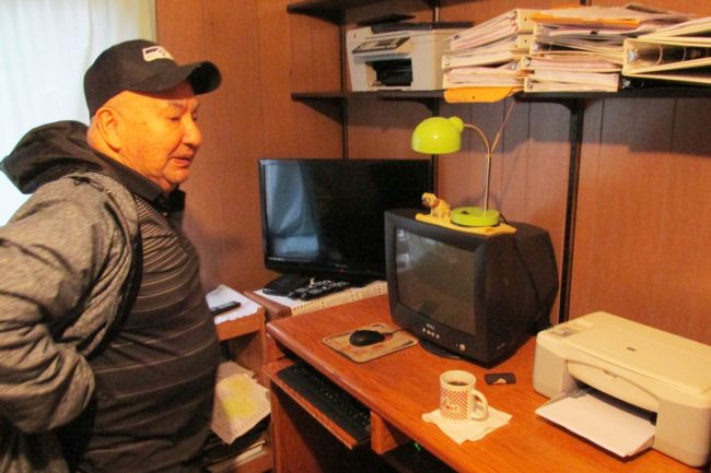 Frank James looks at some of the salvaged electronic equipment and paperwork after the roof of his home blew off early Tuesday morning. (Photo by Leila Kheiry/KRBD)