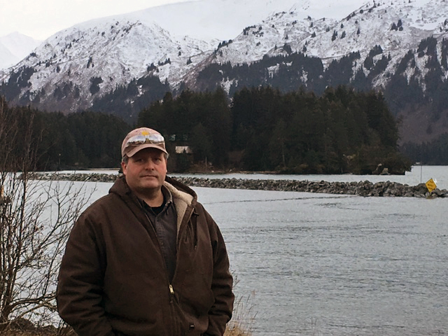 Zane Henning, a friend of Greg Davis, with Backer’s Island in the background. (Photo by Quinton Chandler/KBBI)