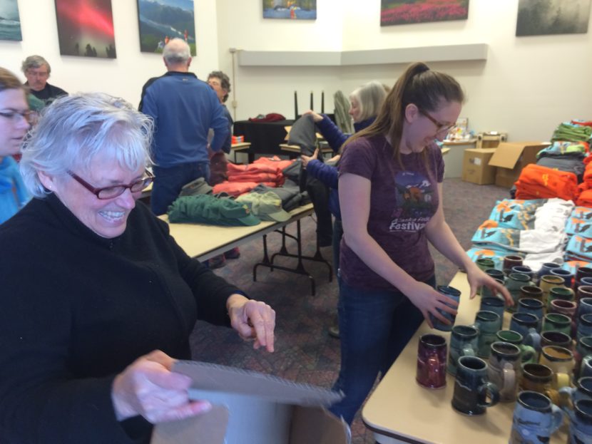 Carol Ackerman and Erin Hanson set up the merchandise table on Sunday. (Photo Scott Burton/KTOO)