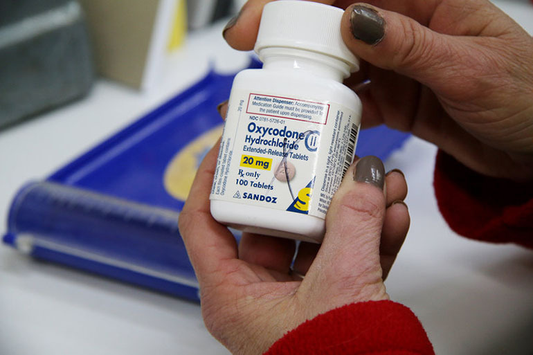 Michelle Pattengill, a technician at L&S Pharmacy in Charleston, Missouri, holds a bottle of oxycodone. (Bram Sable-Smith/Side Effects Public Media/KBIA)