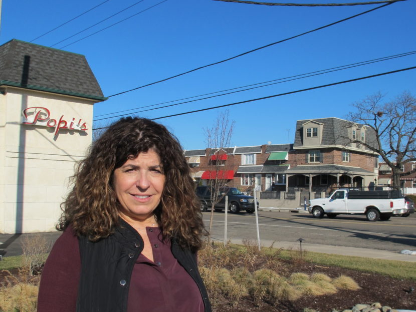 Gina Rucci stands by a new rain garden built in the parking lot of her restaurant in South Philadelphia. The improvements have cut her water runoff bill by 60 percent. Susan Phillips/WHYY