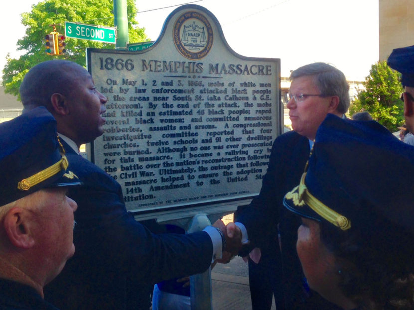 Memphis law enforcement looks on as the Rev. Keith Norman (left), president of the Memphis branch of the NAACP, shakes hands with Memphis Mayor Jim Strickland in front of the new historical marker. Christopher Blank/WKNO-FM