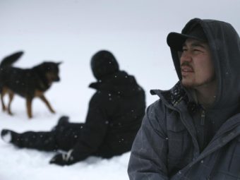 Nathan Tom talks with a reporter while his partner, Sabrina Warner, plays with a dog.
