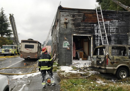 Firefighter Seth Krasnow watches the progress of fire crews as they make sure hot spots are extinguished in a Stedman Street building that caught fire Wednesday. (Leila Kheiry, KHNS)