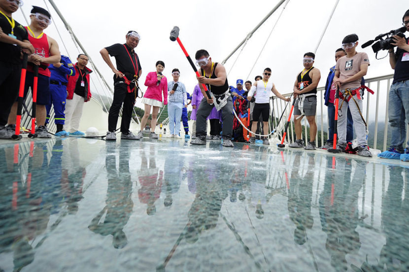A visitor strikes the glass-bottomed bridge with a hammer for a safety test at Zhangjiajie Grand Canyon on June 25. Visual China Group via Getty