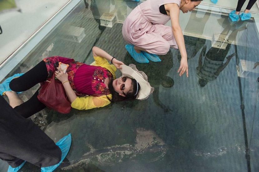 A tourist poses for a photograph on the glass-bottomed bridge above a valley in Zhangjiajie on Saturday. Fred Dufour/AFP/Getty Images