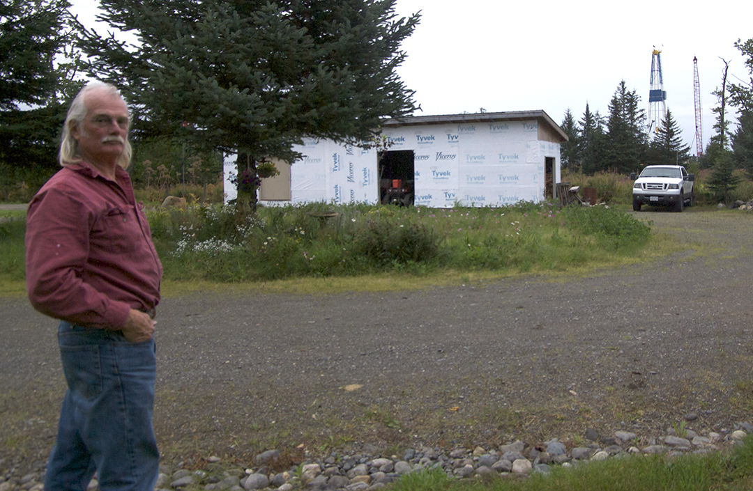 Herff Keith lives next door to BlueCrest Energy's oil drilling pad. A construction crane and new oil drilling rig can be seen in the background. (Photo by Jenny Neyman/KBBI) 