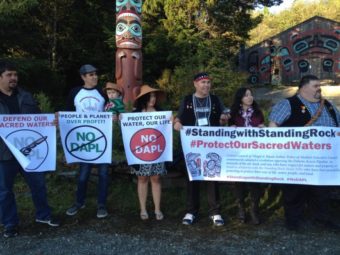 Protesters carry signs opposing the Dakota Access Pipeline. (Photo by KRBD)