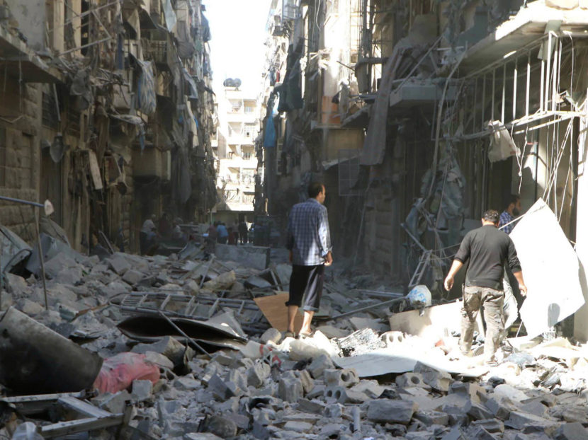 In a photo provided by the Syrian Civil Defense group known as the White Helmets, men inspect damaged buildings in Aleppo, Syria, on Saturday. AP