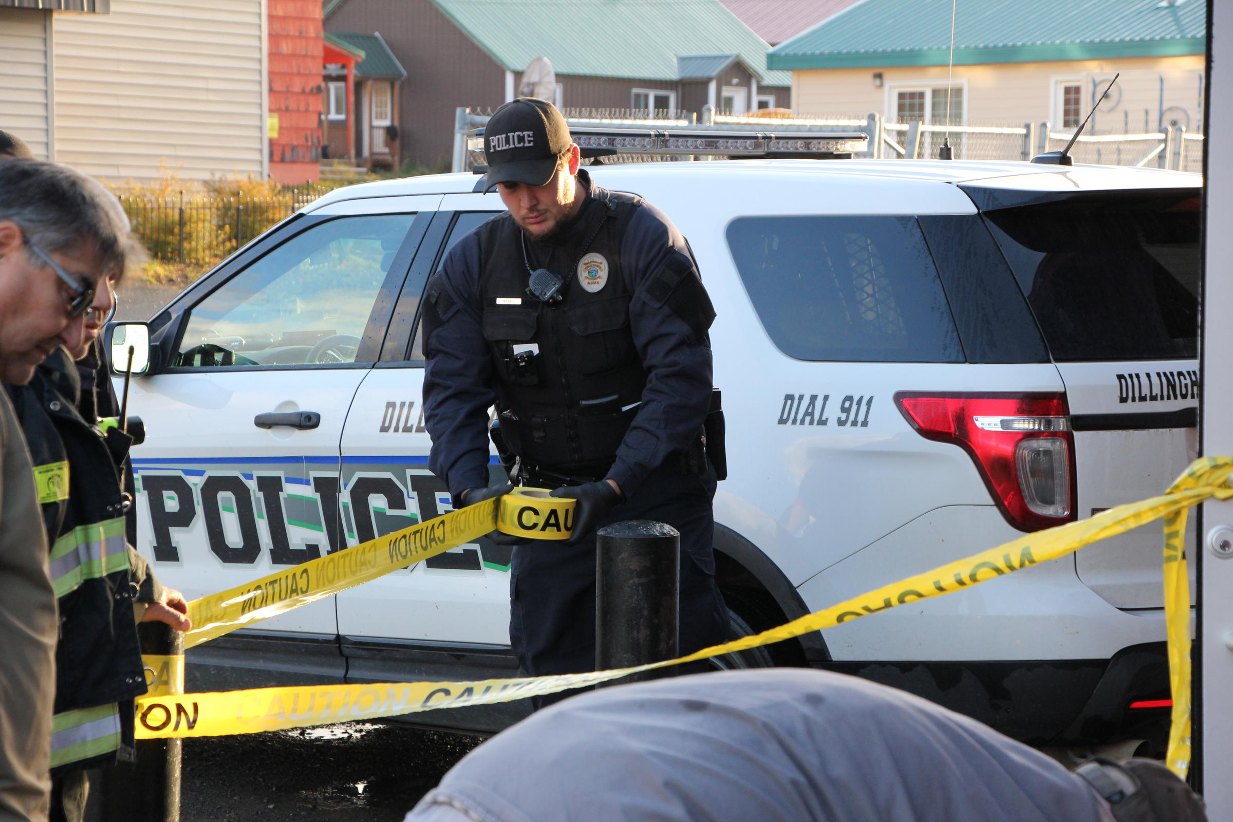 Dillingham Police Officer Craig Maines stretches crime scene tape around the front of the N&N Market in downtown Dillingham, after fires damaged the inside Sunday morning. (Photo by KDLG)