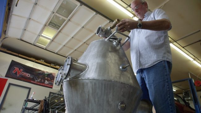 Kevin Kennedy works on a piece of one of his oil spill cleanup devices. (Eric Keto/Alaska's Energy Desk)