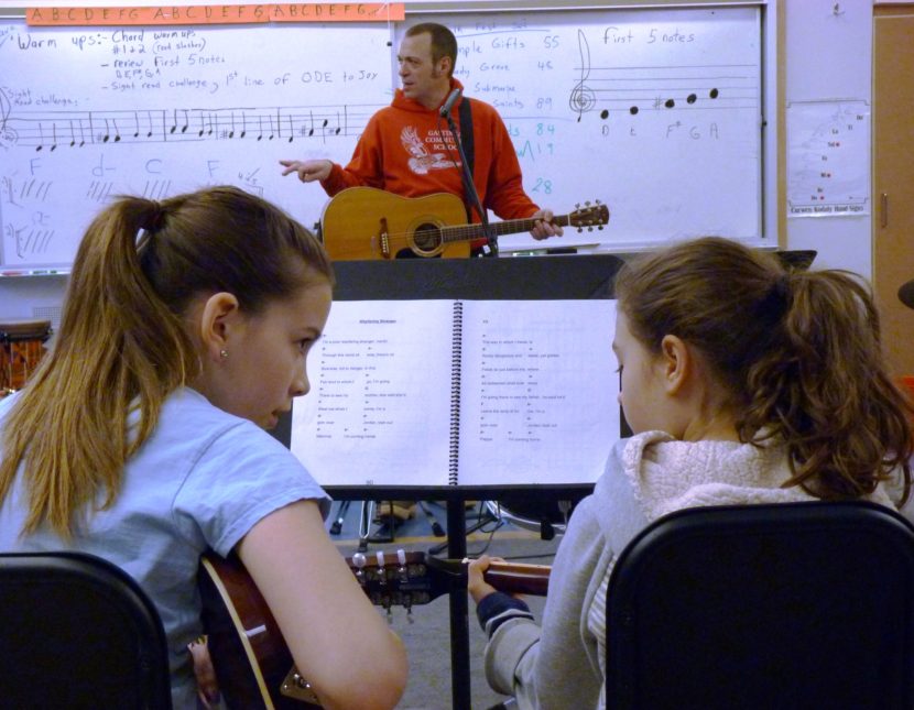 Ruby Rivas and Mila Hargrove discuss a song as teacher Patrick Murphy leads a music class at Gastineau Elementary School in Douglas. (Photo by Ed Schoenfeld/ CoastAlaska News)