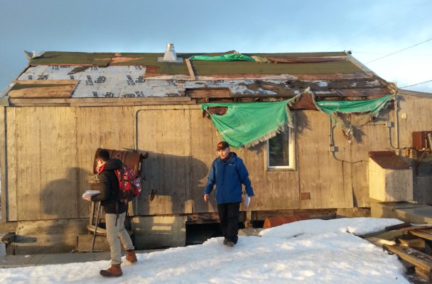 Mayor Myron Kingeekuk and a Red Cross employee survey storm-damaged homes in the community. (Photo by Davis Hovey/KNOM)