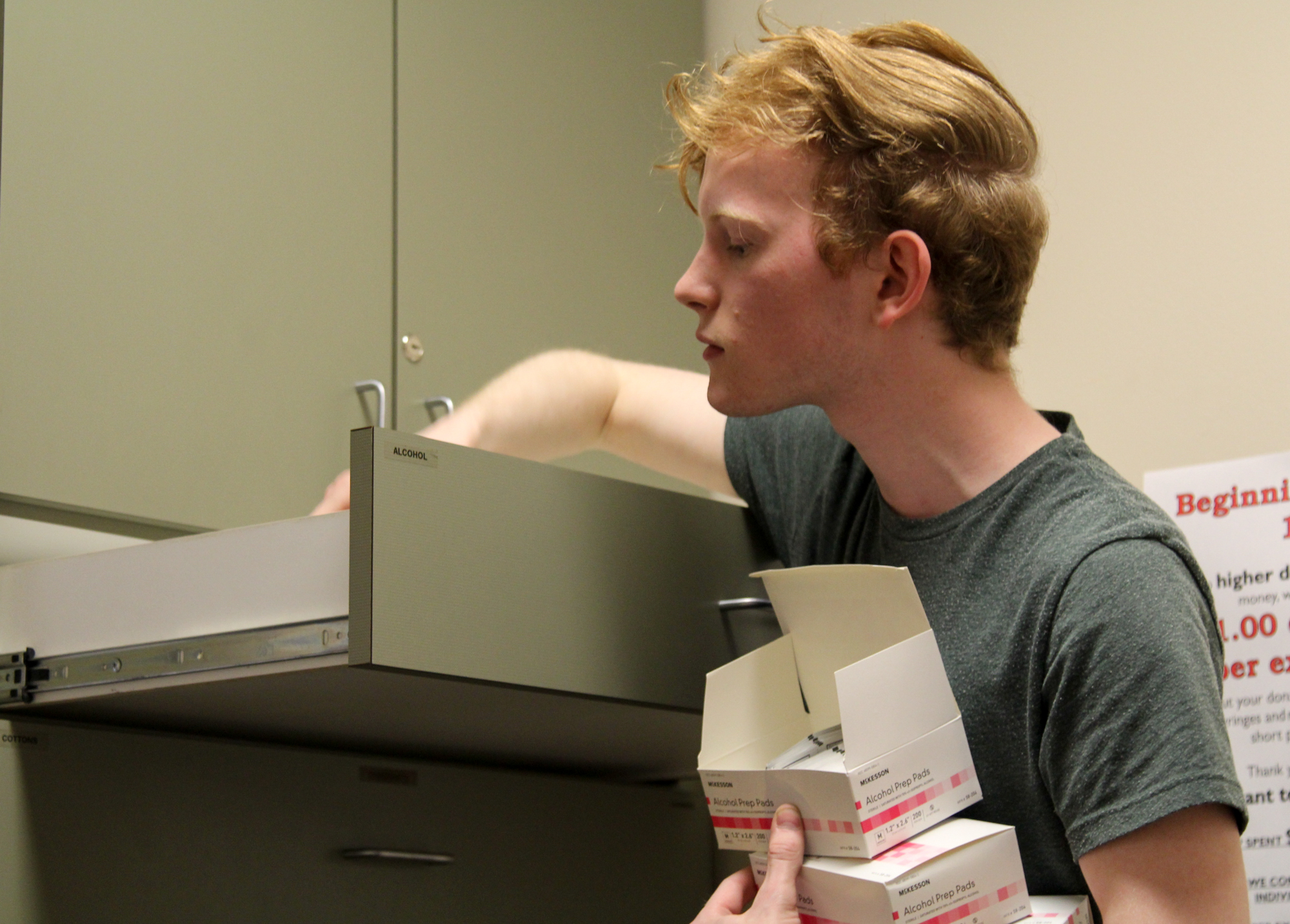 Volunteer Zane Davis restocks alcohol swabs and other supplies at the Alaska AIDS Assistance Association’s Anchorage office. (Photo by Zachariah Hughes/Alaska Public Media)