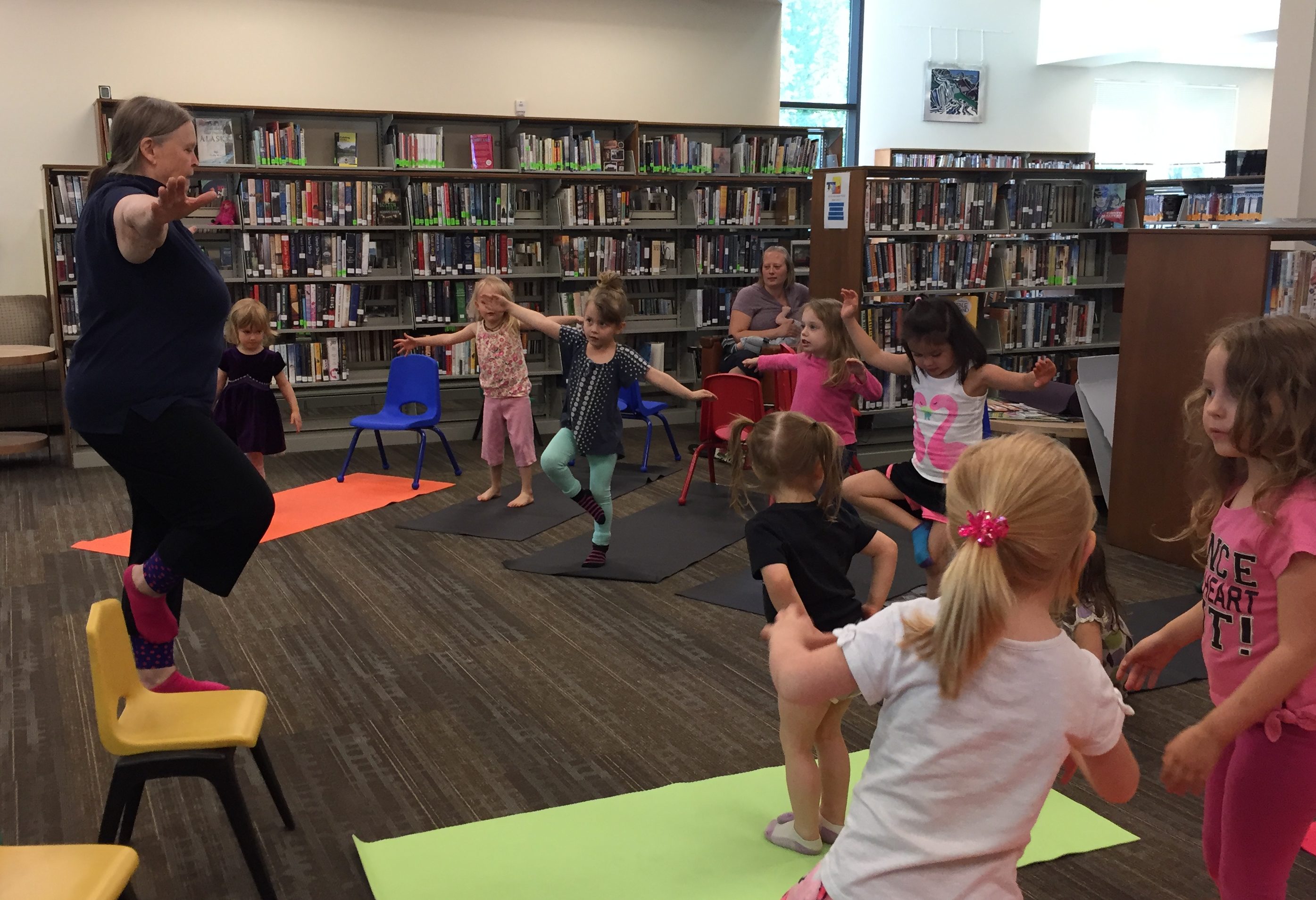 Geri Denkewalter teaches yoga to children at the Talkeetna Public Library before the lunch program begins. (Photo by Anne Hillman/Alaska Public Media)