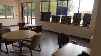 Tables and chairs in the common room with windows looking out into the parking lot