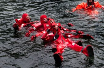 In a formation called "the worm," crewmen link up to be able to paddle against strong waves and winds to a lifeboat. (Photo by Jesse Costa/WBUR)