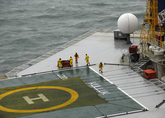 A salvage team aboard the conical drilling unit Kulluk moves an emergency towing system delivered the Kulluk by a Coast Guard MH-60 Jayhawk helicopter Wednesday, Jan. 2, 2013. The Kulluk is located 40 miles southwest of Kodiak City, Alaska, on the shore of Sitkalidak Island. U.S. Coast Guard photo by Petty Officer 1st Class Travis Marsh