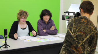 News anchors Kate and Kenny rehearsing for morning announcements while Hunter sets up technical equipment. Photo by Alexander Duerre.