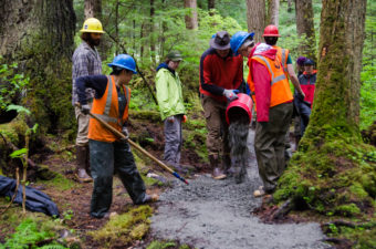 Volunteers dump and smooth bucket after bucket of gravel.