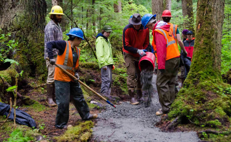 Volunteers dump and smooth bucket after bucket of gravel.