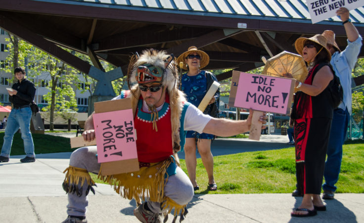 John Smith the 3rd dances with protest signs at the Idle No More rally at Marine Park.