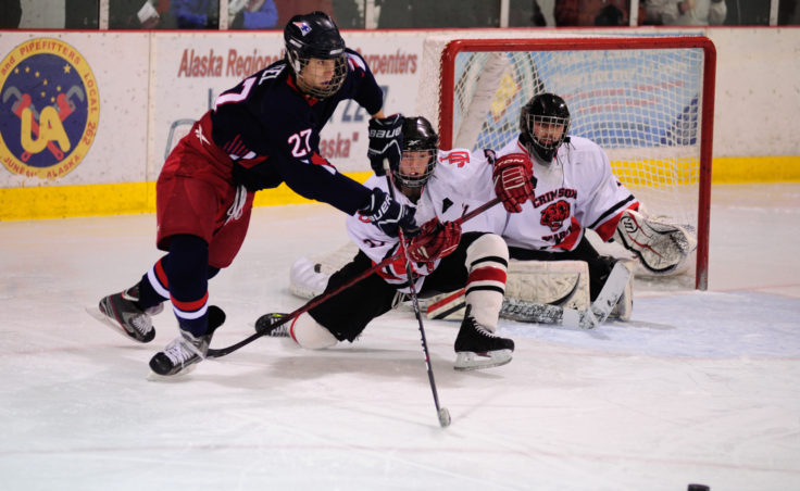 Juneau defenseman Michael Dale stretches to keep North Pole’s Carmon Teel from getting to teammate, goalie Neil Chapman.