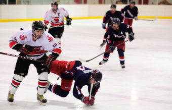 Juneau’s Logan Moser puts the finishing touches on an open-ice check to North Pole’s Wyatt Conrow during Saturday’s game at Treadwell Ice Arena.