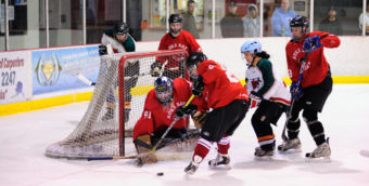 Killer Whales’ Becca Parks looks to clear the puck from the crowd gathering in front of goalie Jason Soza.