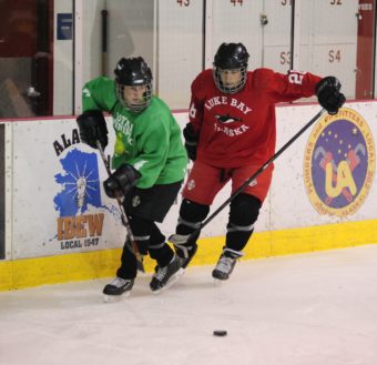 Suzanne McGee (left) and Griffin McKinney battle for the puck while coming round the net and along the boards.