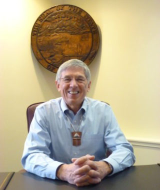 Lt. Gov. Byron Mallott sits at his desk, beneath the state seal Feb. 26. Mallott heads up a new administration transboundary mines working group. (Ed Schoenfeld/CoastAlaska News)