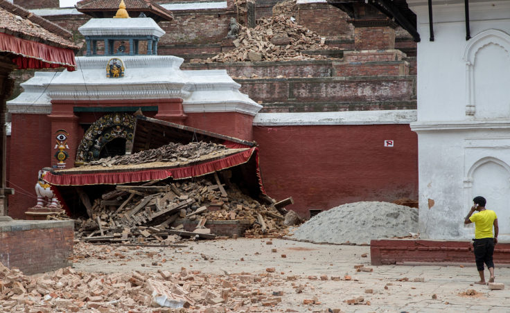 A young man speaks on the phone in front of a collapsed temple in the city center following an earthquake on April 25, 2015 in Kathmandu, Nepal. A strong magnitude-7.8 earthquake shook Nepal's capital and the densely populated Kathmandu Valley before noon Saturday, causing extensive damage (Photo by Omar Havana/Getty Images)