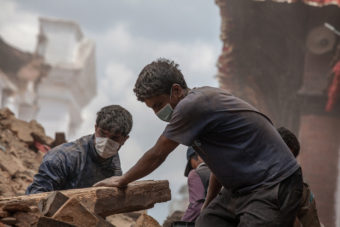 Volunteers clear debris of a collapsed temple