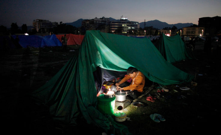 A Nepalese man cooks food inside a tent as people relocate to open ground from fears of earthquake tremors in Kathmandu, Nepal, on Monday evening. (Photo by Niranjan Shrestha/AP)