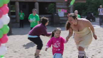 Council Director Ati Nasiah helps a younger runner across the finish line (Photo by David Purdy/KTOO)