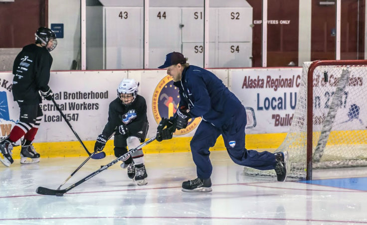 Rocky Mountain Hockey School coach Billy Barto plays keep away from Juneau youth player Busby. (Photo by Steve Quinn)